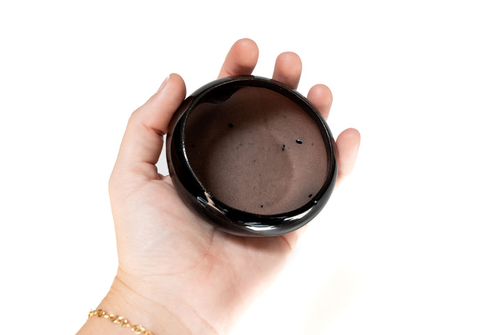 hand holding black glazed ceramic dish