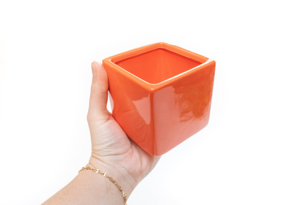 hand holding orange ceramic cube planter