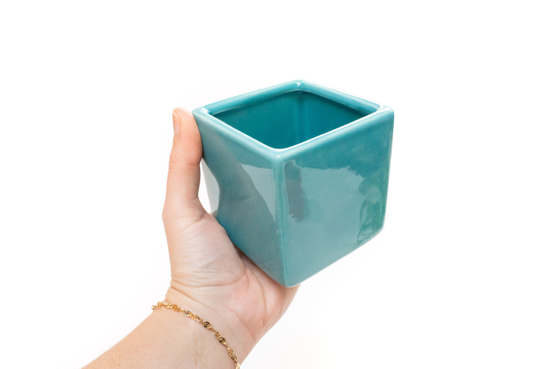 hand holding blue ceramic cube planter